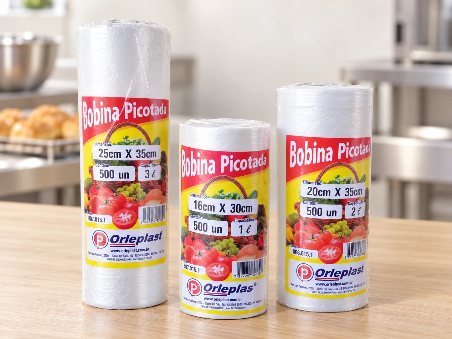 Três bobinas picotadas Orleplast lado a lado, nos tamanhos 16x30, 20x35 e 25x35 cm, com a contagem de 500 unidades no rótulo